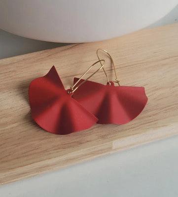 Boucles d’oreilles fantaisie rouges en forme de fleur sur fond bois clair
