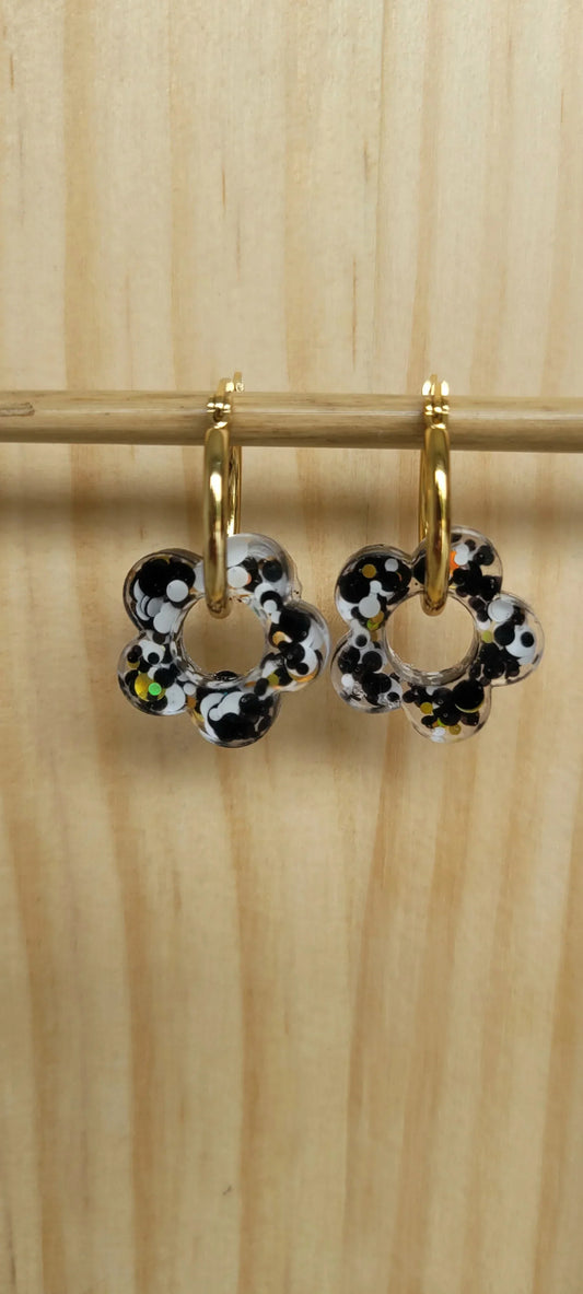 Boucles d’oreilles créoles dorées avec pendentifs fleurs en résine noire, blanche et jaune pailletée