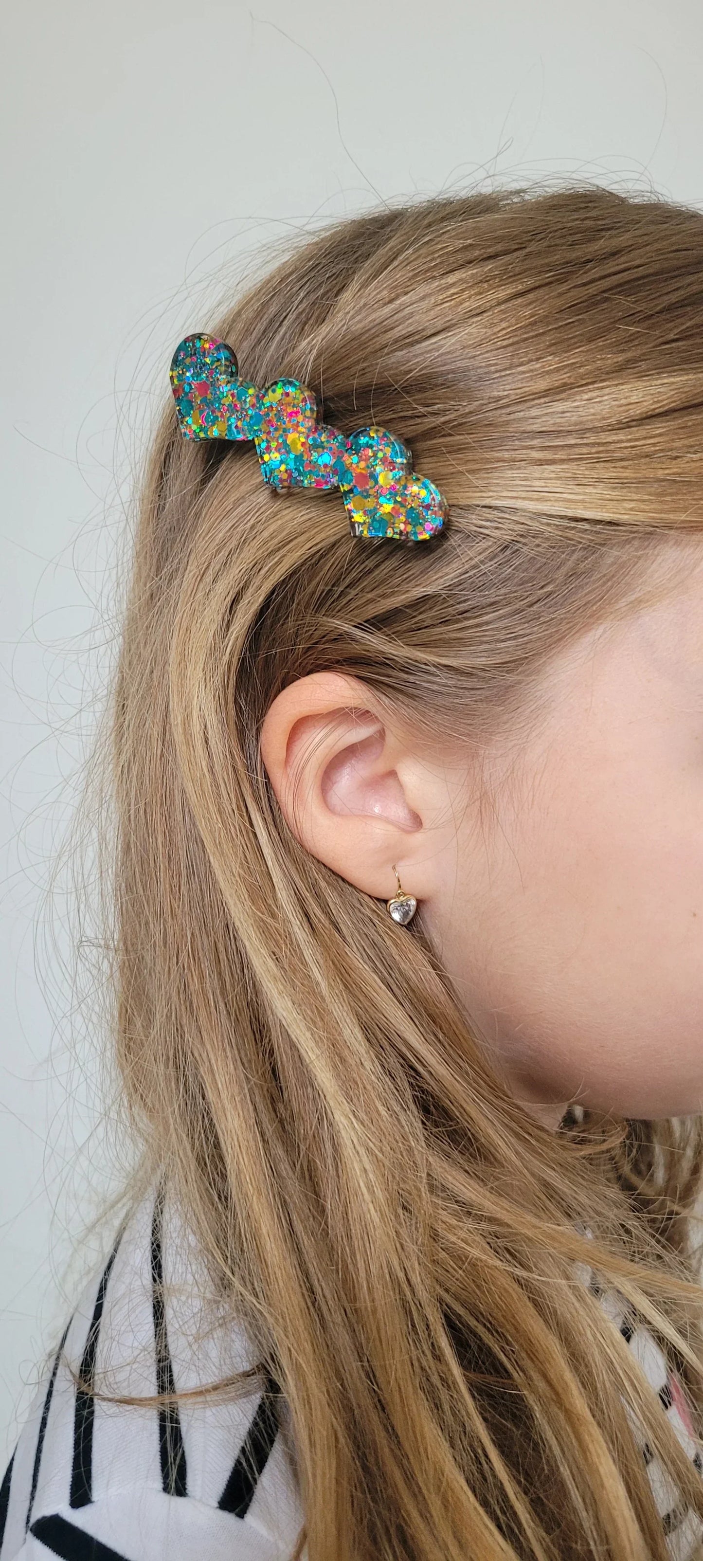 Barrette en résine paillettes multicolores forme cœur portée sur cheveux blonds