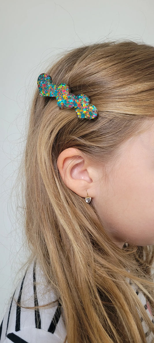 Barrette en résine paillettes multicolores forme cœur portée sur cheveux blonds